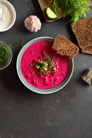Beet cream soup with yogurt, cucumbers and dill in bowl on dark background with free space. Cold summer soup. Top view, flat layの写真素材