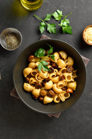 Pipe rigate pasta with roasted mushrooms served in black bowl on dark stone background. Top view, flat layの写真素材