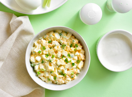 Egg salad with green onion in bowl over green background. Top view, flat layの写真素材