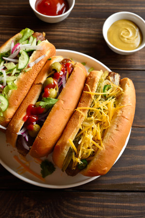 Hot dogs loaded with assorted toppings on wooden table. Close up viewの写真素材