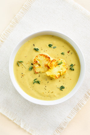 Cauliflower cheese soup in bowl over light background. Vegetarian or healthy diet food concept. Top view, flat layの写真素材