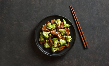 Beef with broccoli on plate over dark stone background. Thinly sliced beef meat with roasted broccoli. Top view, flat layの写真素材