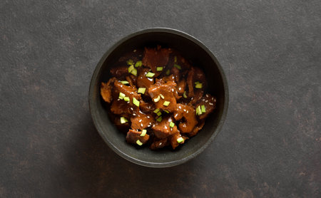 Beef with soy sauce, green onion and sesame seeds in bowl over dark stone background. Top view, flat layの写真素材