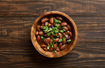 Baked beans with greens in bowl on wooden background. Top view, flat layの写真素材