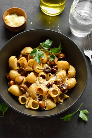 Pipe rigate pasta with roasted mushrooms garnished with fresh parsley served in black bowl on dark stone background. Close up viewの写真素材