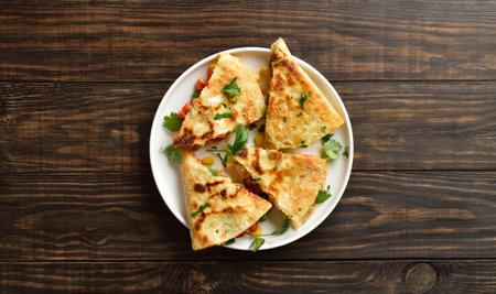 Chicken quesadillas with fresh vegetables on white plate on brown wooden background. Top view, flat layの写真素材