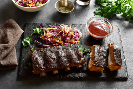 Spicy grilled spare ribs on stone serving board on dark background. Close up viewの写真素材