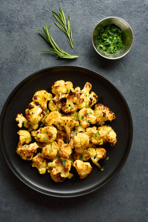 Roasted cauliflower on black plate over blue stone background. Top view, flat layの写真素材