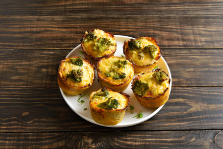 Healthy loaded egg muffins made with eggs, ham, broccoli, cheese on brown wooden background. Tasty meal for breakfast or lunch. Close up viewの写真素材