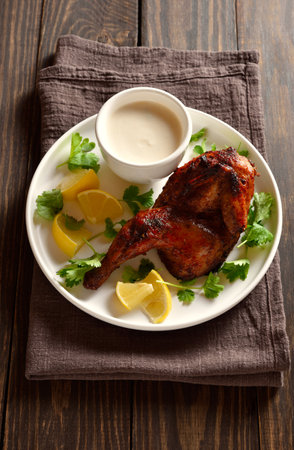 Roasted half chicken on white plate on wooden table. Tasty grilled chicken meat for dinner. Close up viewの写真素材