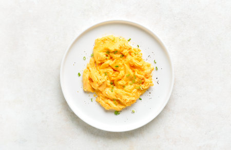 Scrambled eggs on white plate on light background. Healthy diet eating concept. Top view, flat layの写真素材