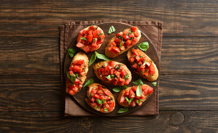 Bruschetta with cherry tomatoes and basil on brown wooden background. Top view, flat layの写真素材