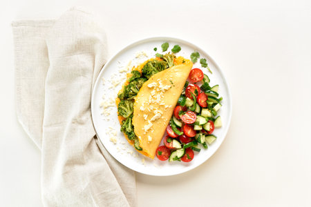Omelet with roasted broccoli and cheese served with salad from fresh vegetables on white plate on light background. Healthy diet food concept. Top view, flat layの写真素材