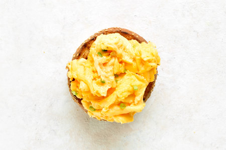Diet scrambled eggs on toasted brioche bun on light background. Tasty meal for breakfast or brunch. Top view, flat layの写真素材