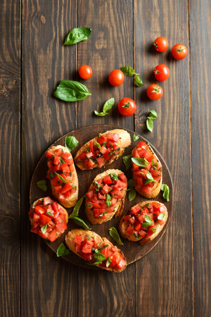 Bruschetta with cherry tomatoes and basil on brown wooden background. Top view, flat layの写真素材