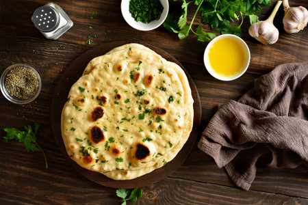 Homemade Indian naan bread with garlic butter on wooden table. Top view, flat layの写真素材
