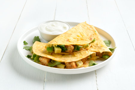 Chicken avocado quesadillas served with sauce on plate on white wooden background. Close up viewの写真素材