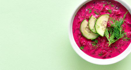 Close up view of cold summer beetroot soup in bowl over green background with copy space. Healthy detox or vegetarian food concept. Top view, flat layの写真素材