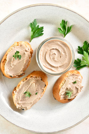 Close up view of chicken liver pate on toasted bread on plate over light background. Top view, flat layの写真素材