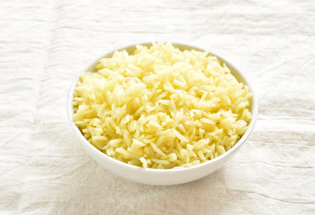 Cooked saffron rice in white bowl on light tablecloth. Close up viewの写真素材