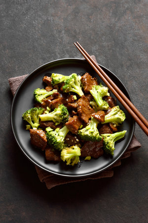 Beef with broccoli on black plate over dark stone background. Thinly sliced beef meat with roasted broccoli. Close up viewの写真素材