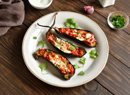 Roasted aubergine with yogurt and spicy tomato sauce dressing over wooden table. Close up viewの写真素材