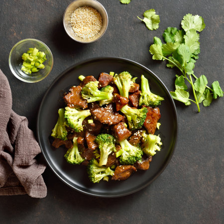 Thinly sliced beef meat with roasted broccoli. Beef with broccoli on plate over dark stone background. Top view, flat layの写真素材