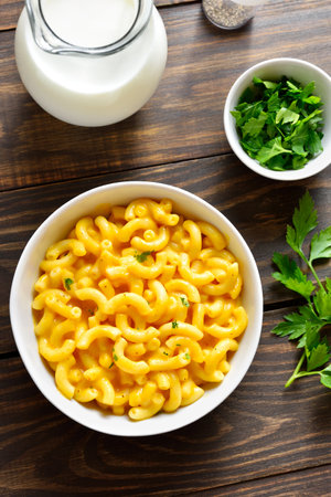 Homemade macaroni and cheese in white bowl on wooden table. Top view, flat layの写真素材
