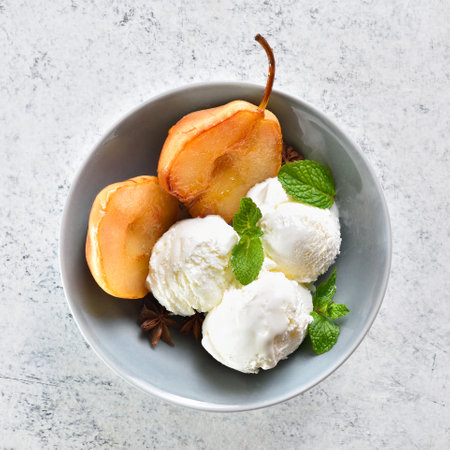 Poached pears with ice cream in bowl on light stone background. Summer dessert. Top view, flat layの写真素材