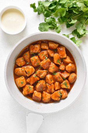 Sweet and spicy chicken bites with sauce in skillet on white background. Top view, flat layの写真素材