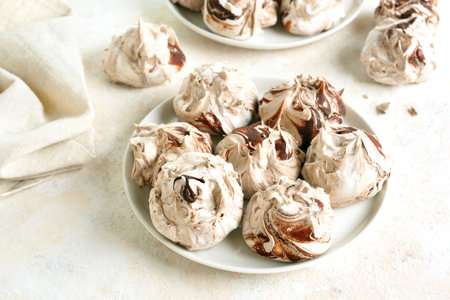 Homemade chocolate meringue cookies on white plate on light background. Close up viewの写真素材