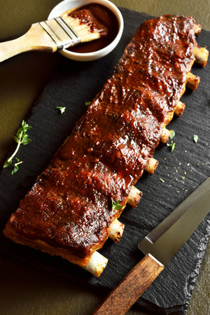 Bbq spare ribs on slate serving board on dark background. Close up viewの写真素材