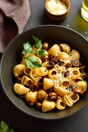 Pipe rigate pasta with roasted mushrooms garnished with fresh parsley served in black bowl on dark stone background. Close up viewの写真素材