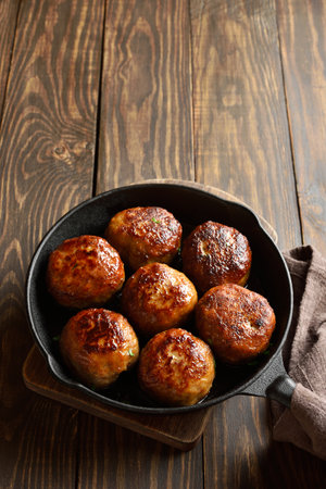 Minced pork and beef cutlets in cast iron skillet on wooden background with free space for textの写真素材