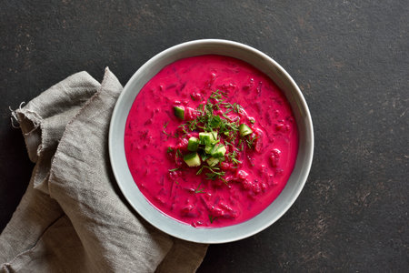 Beet cream soup with yogurt, cucumbers and dill in bowl on black stone background. Cold summer soup. Top view, flat layの写真素材