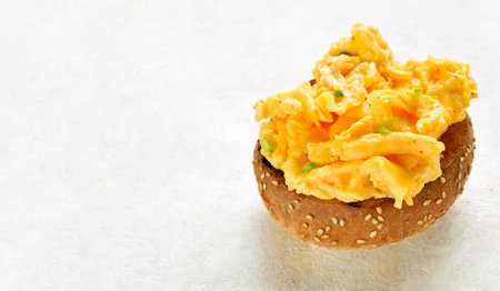 Scrambled eggs on toasted brioche bun on light background with free space. Tasty meal for breakfast or brunch. Close up viewの写真素材