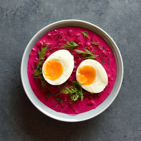 Close up view of cold summer beet soup with cucumbers, dill and egg in bowl on dark stone background. Top view, flat layの写真素材