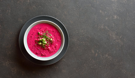 Beet cream soup with yogurt, cucumbers and dill in bowl on dark background with free space. Cold summer soup. Top view, flat layの写真素材