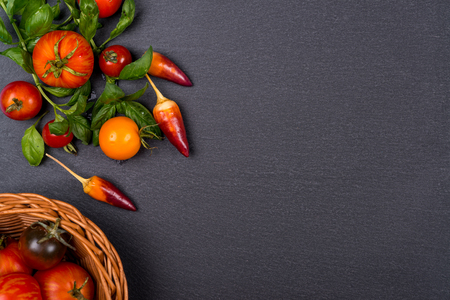 Fresh tomatoes,pepper and basil on black slate. Space for text.の写真素材
