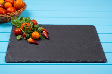 Fresh tomatoes,pepper and basil on black slate. Space for text.の写真素材