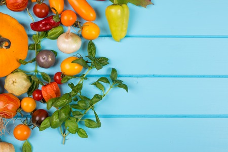 Vegetable background. Fresh peppers, tomatoes, basil, zucchini,pumpkin,spices and seasoning on the blue wooden background. Organic food concept. Space for text.の写真素材
