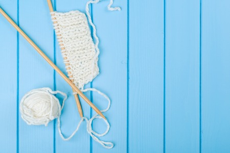 Knitted white scarf and hat on the blue wooden background.の写真素材