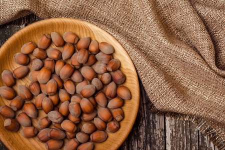 Hazelnuts in a wooden bowl on the dark background.の写真素材