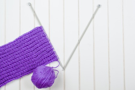 Knitting purple scarf close up on the wooden white table.の写真素材