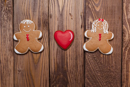 Gingerbread man and women with a heart on the wooden background.の写真素材