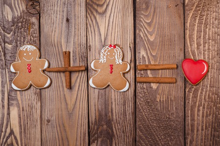 Gingerbread man and women with a heart on the wooden background.の写真素材