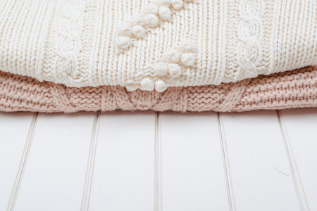 Two modern knitted sweaters on the white wooden background.