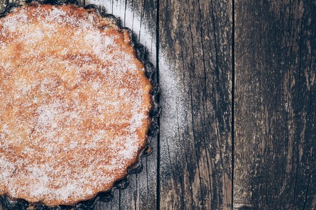 Homemade pie sprinkled with powdered sugar on the rustic wooden background. Space for text.の写真素材