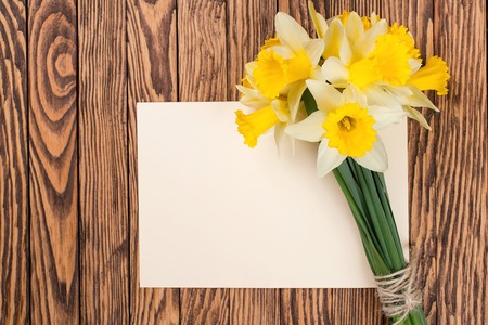 Fresh  spring yellow  daffodils  flowers and empty tag on a brown painted wooden planks. Selective focus. Place for text.の写真素材