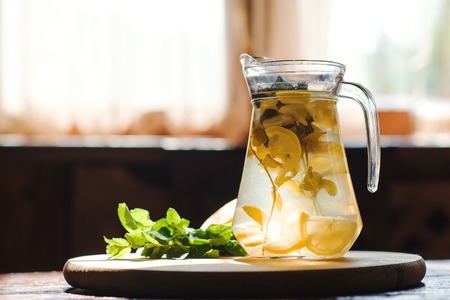 Fresh Lemonade in jar with yellow lemon and mint on the wooden kitchen background. Water Detox.の写真素材